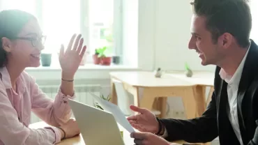 Dos personas conversando en una oficina luminosa.