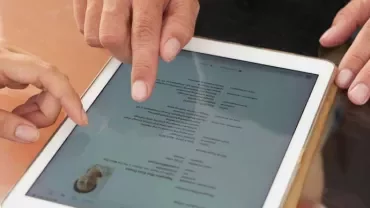 Personas discuten contenido en tablet en mesa.