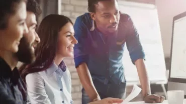 Grupo de personas mirando una pantalla de computadora.