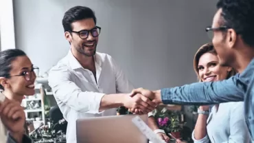 Personas en reunión, sonriendo y estrechando manos.