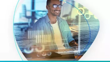 Persona sonriendo, frente a una pantalla de computadora con gráficos.