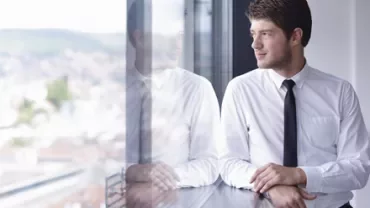 Persona mirando por la ventana en un edificio alto.