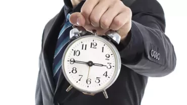 Persona sosteniendo un reloj despertador grande de manecillas.