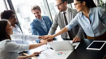 Grupo de personas juntando las manos en una oficina moderna.