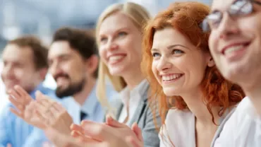 Grupo de personas aplaudiendo y sonriendo en un evento.