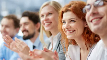 Grupo de personas aplaudiendo y sonriendo en un evento.