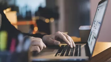 Persona usando una laptop en una mesa con luz suave.