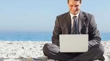 Persona trabajando con laptop en la playa.