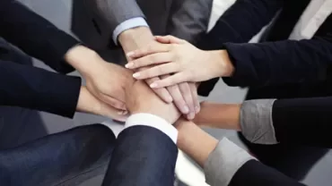 Manos unidas formando un círculo de colaboración.