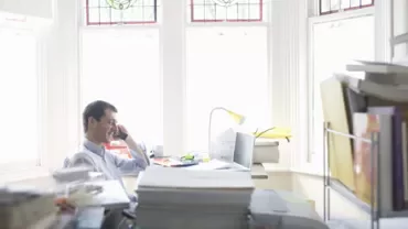 Persona hablando por teléfono en una oficina luminosa.