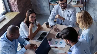 Grupo de personas trabajando en una oficina con laptops y gráficos.