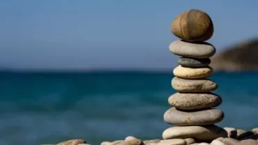 Piedras apiladas frente a un mar tranquilo.