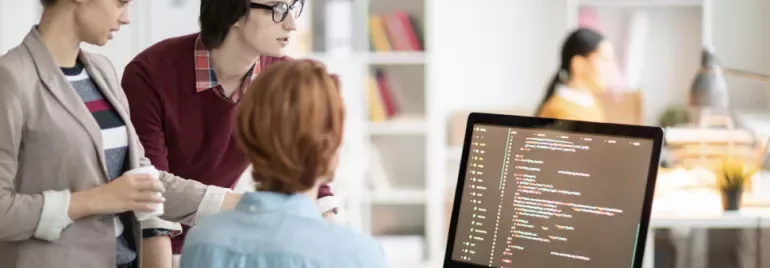 Personas colaborando frente a una pantalla de código.