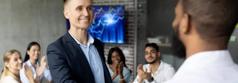 Personas dando un apretón de manos en una reunión de oficina.