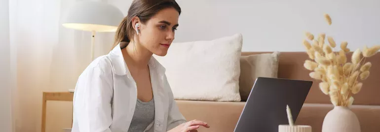 Mujer con audífonos frente a una computadora 