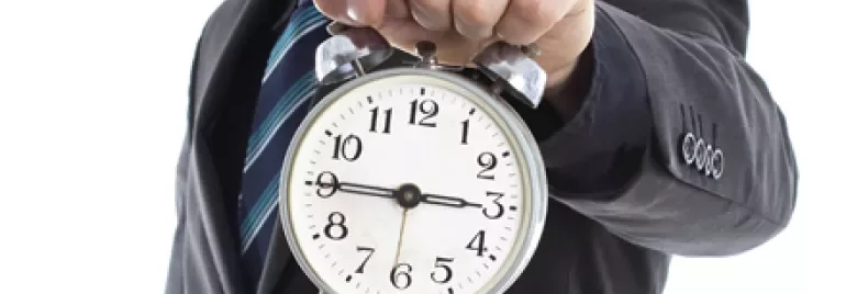 Persona sosteniendo un reloj despertador grande de manecillas.