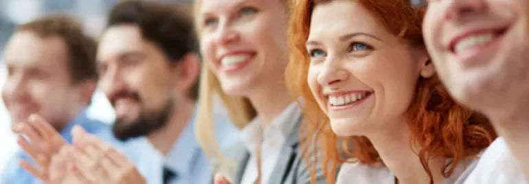 Grupo de personas aplaudiendo y sonriendo en un evento.