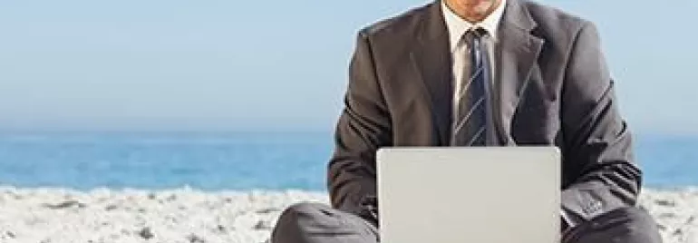 Persona trabajando con laptop en la playa.