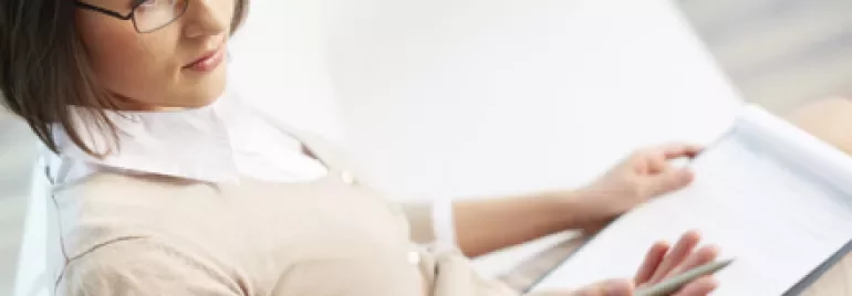 Persona con gafas sosteniendo un cuaderno y un bolígrafo.