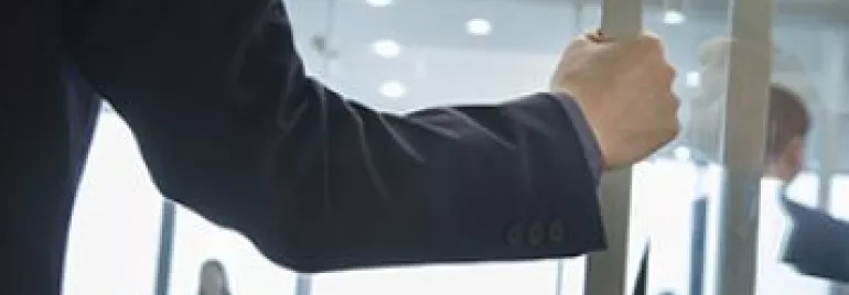 Persona abriendo una puerta de cristal en una oficina.