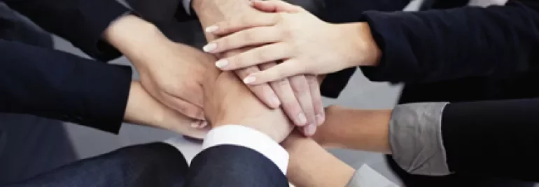 Manos unidas formando un círculo de colaboración.