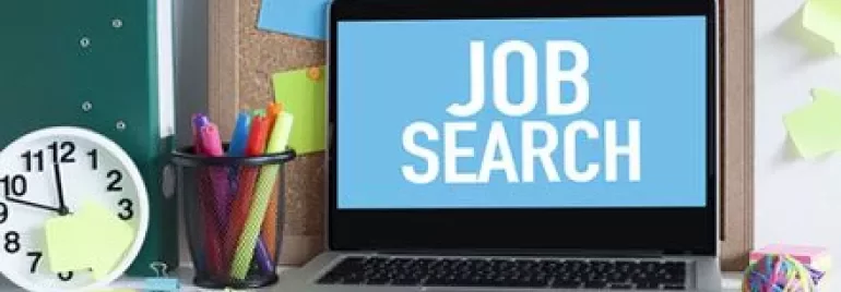 Portátil con pantalla de 'búsqueda de empleo' en un escritorio organizado.