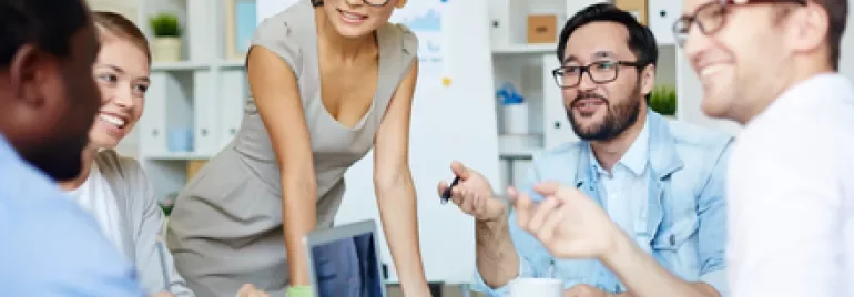 Grupo de personas en una reunión de trabajo con laptops y notas.