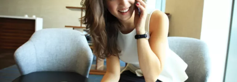 Persona hablando por teléfono mientras toma notas en una oficina.