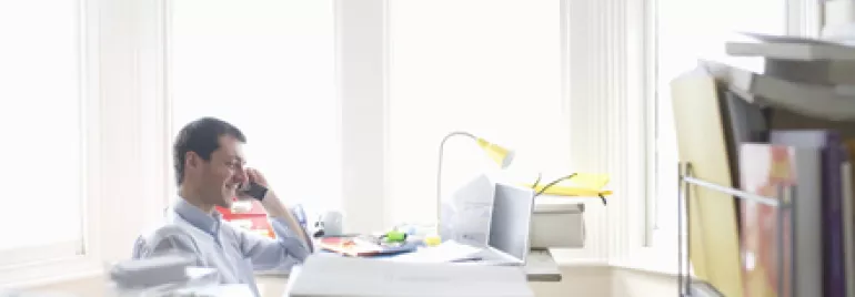 Persona hablando por teléfono en una oficina luminosa.
