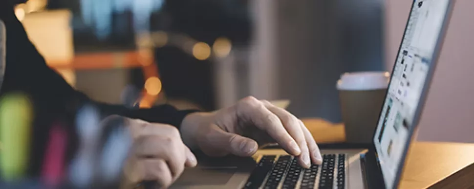 Persona usando una laptop en una mesa con luz suave.