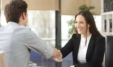 Dos personas dándose la mano en un entorno profesional.