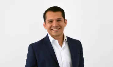 Persona sonriente con traje azul y camisa blanca.