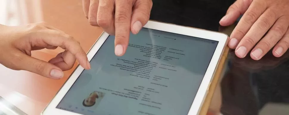 Personas discuten contenido en tablet en mesa.