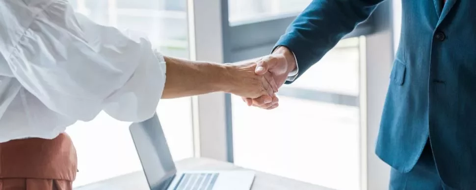 Dos personas dando la mano en una oficina.