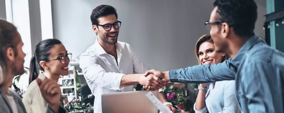 Personas en reunión, sonriendo y estrechando manos.