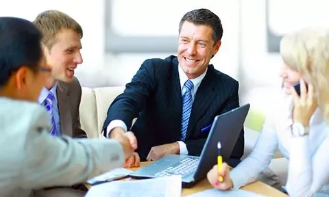 Grupo de personas en una reunión de negocios estrechando manos.