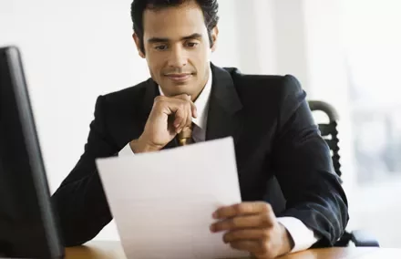 Persona en traje revisa un documento en su escritorio.