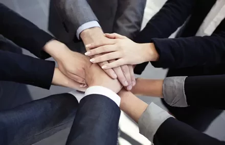 Manos unidas formando un círculo de colaboración.
