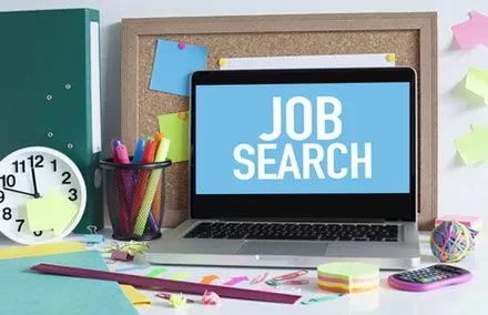 Portátil con pantalla de 'búsqueda de empleo' en un escritorio organizado.