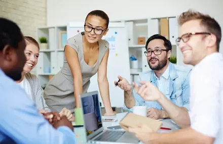Grupo de personas en una reunión de trabajo con laptops y notas.
